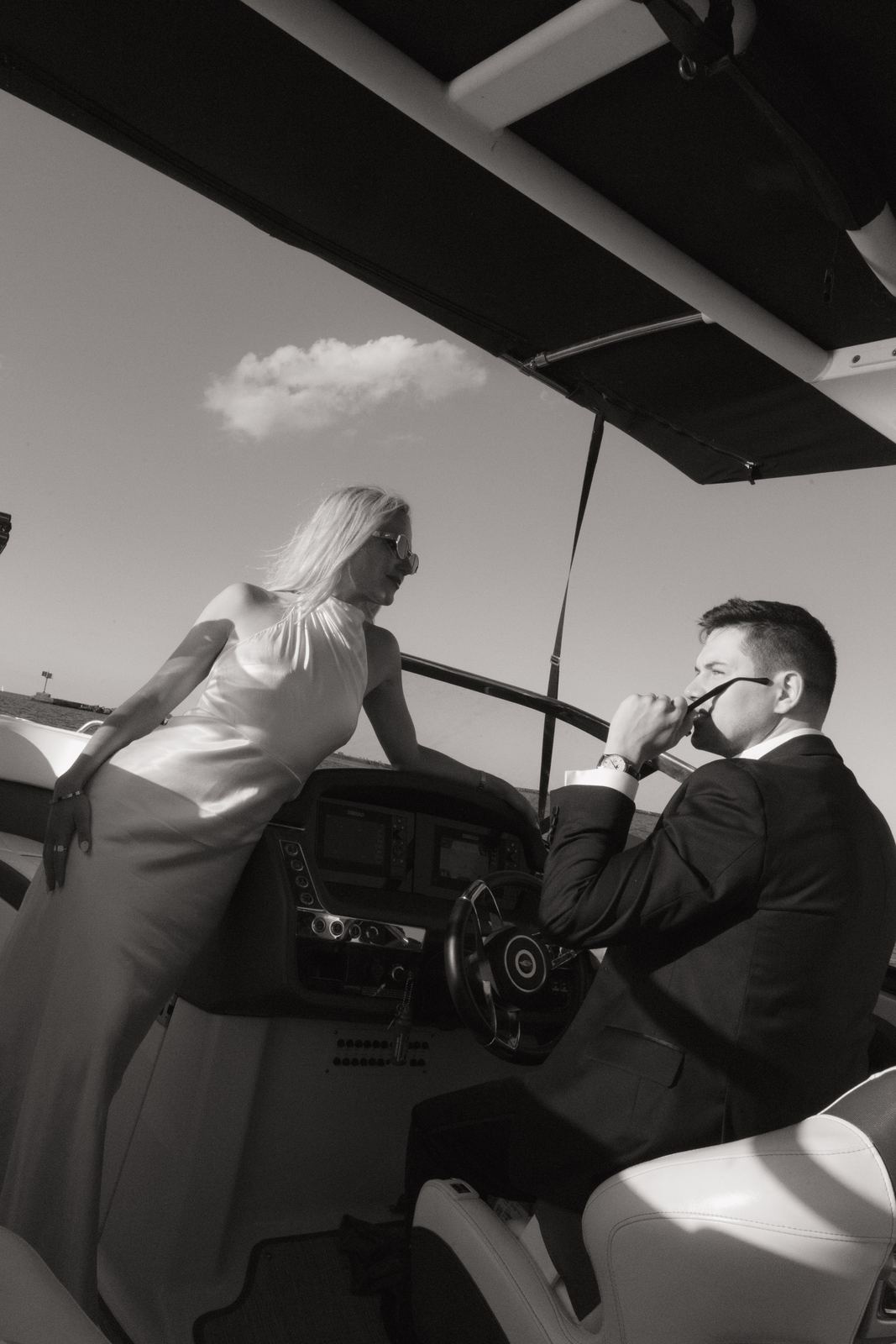 Couple in formal wear aboard a motorboat, the groom at the wheel