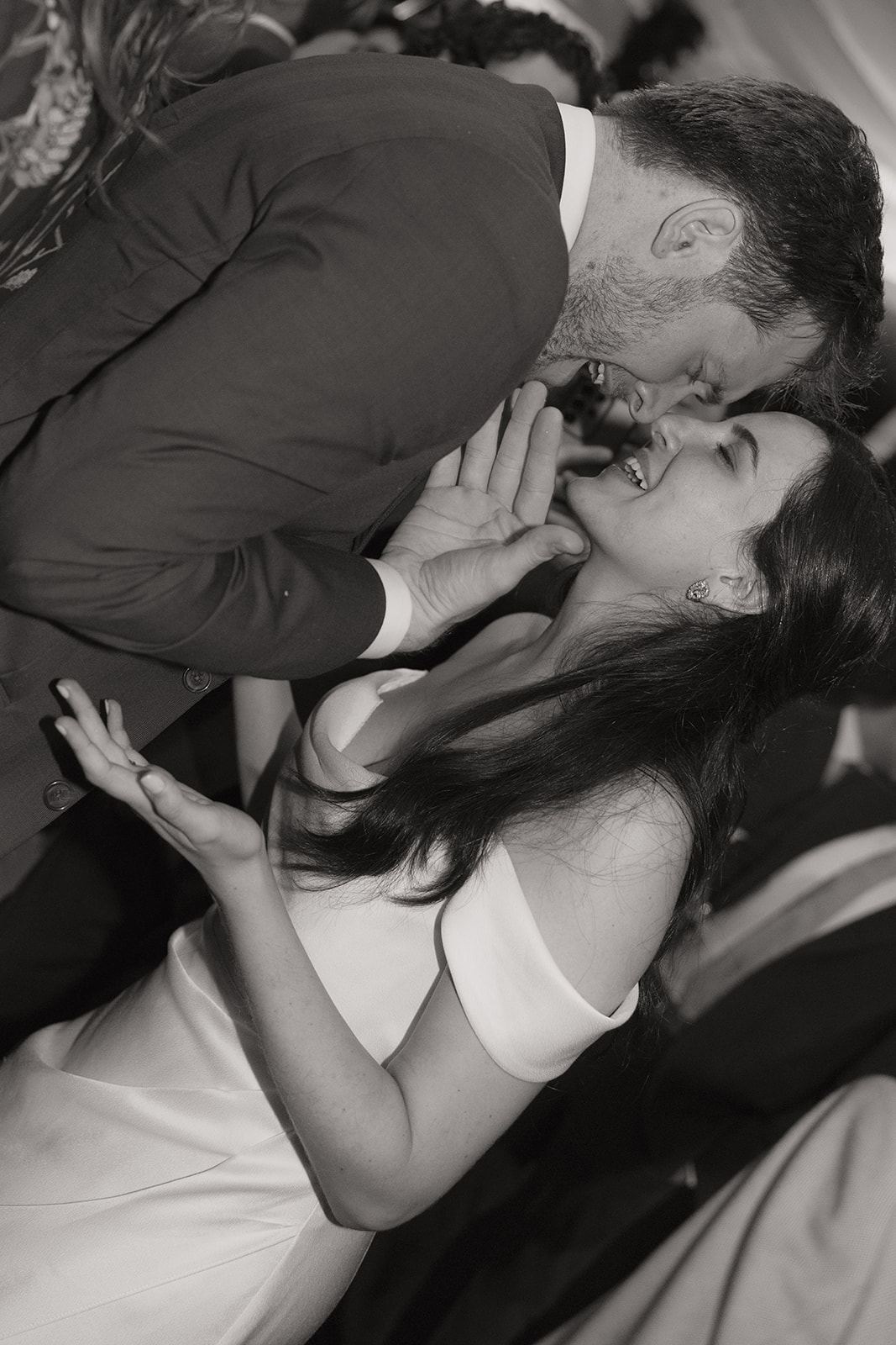 Groom leaning in to kiss the laughing bride
