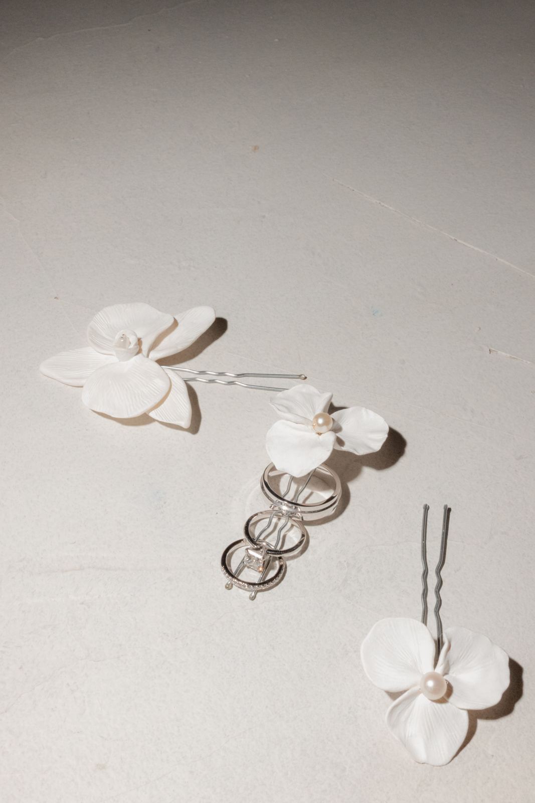 Flower hairpins and wedding rings laid out on linen