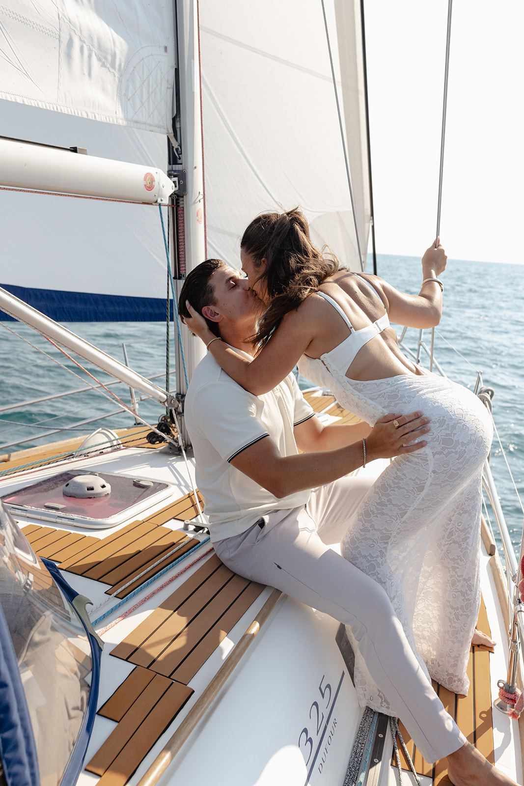 Couple kissing on the deck of a sailboat on open water