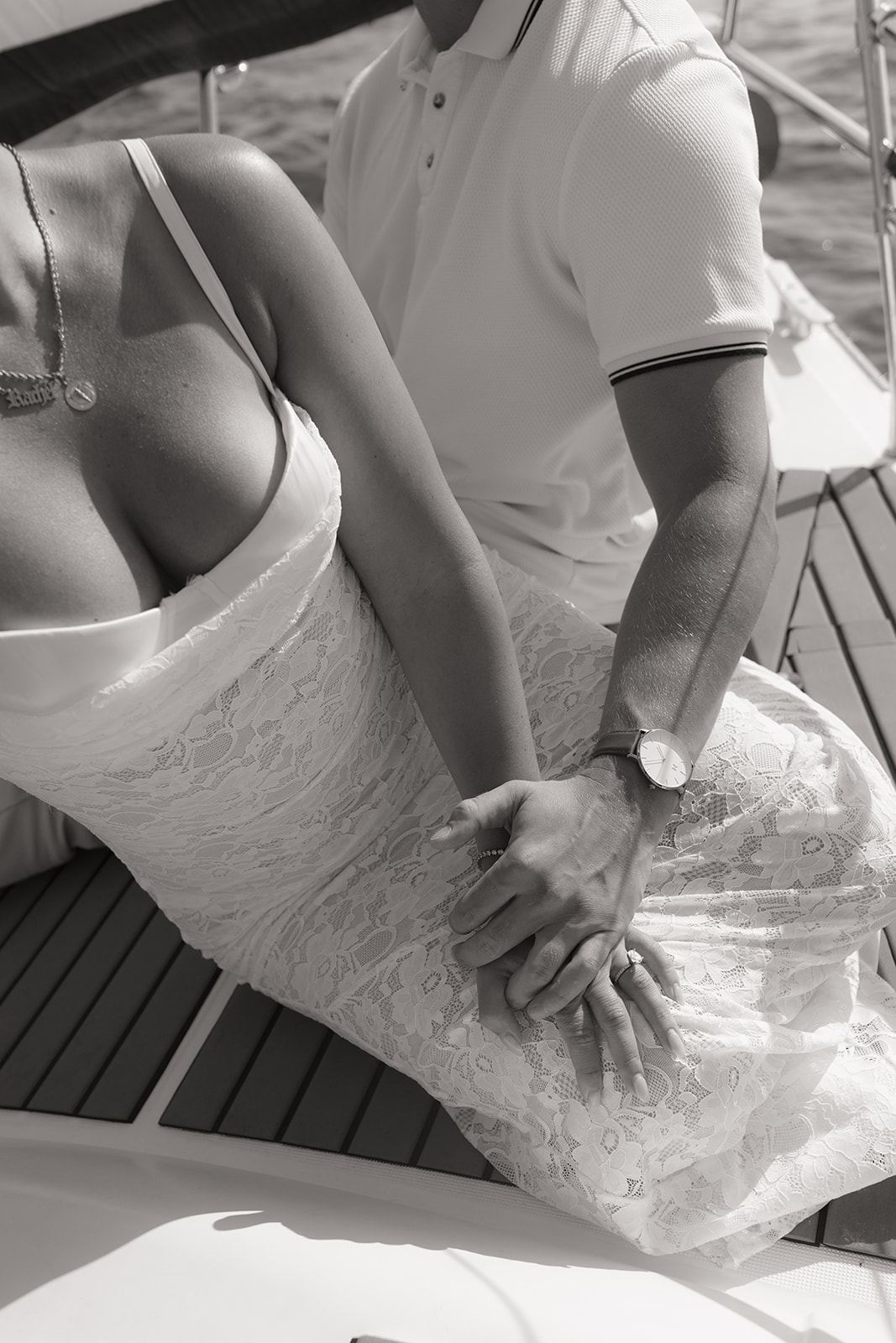 Close-up of a couple's clasped hands as they sit on a boat deck