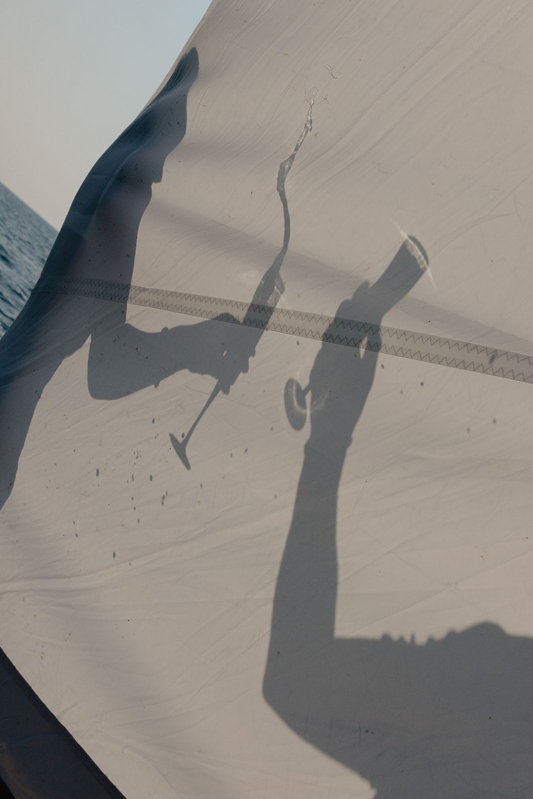 Shadows of a couple toasting with champagne cast on a white sail