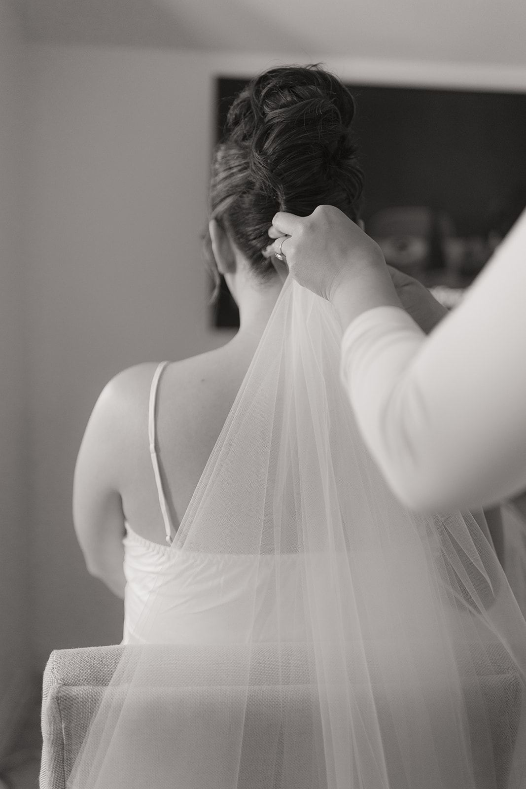 Hands arranging the veil over the bride's bare back