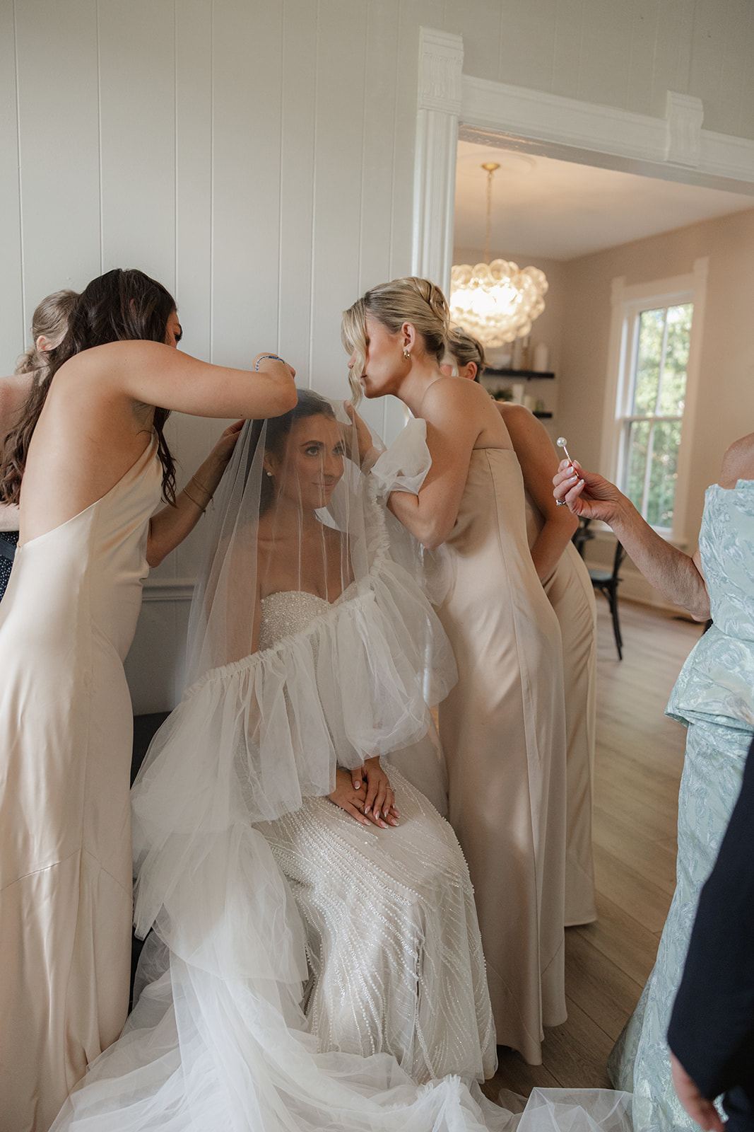 Bridesmaids adjusting the veil of the seated bride
