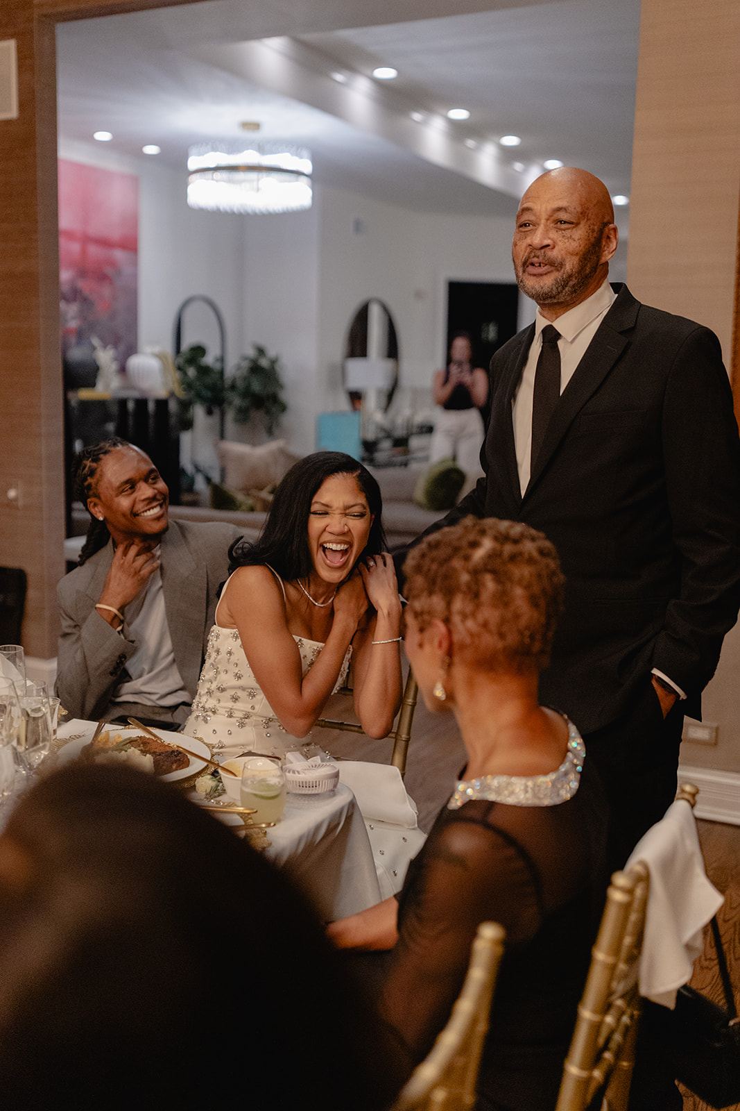 Bride laughing with guests during a lively reception dinner