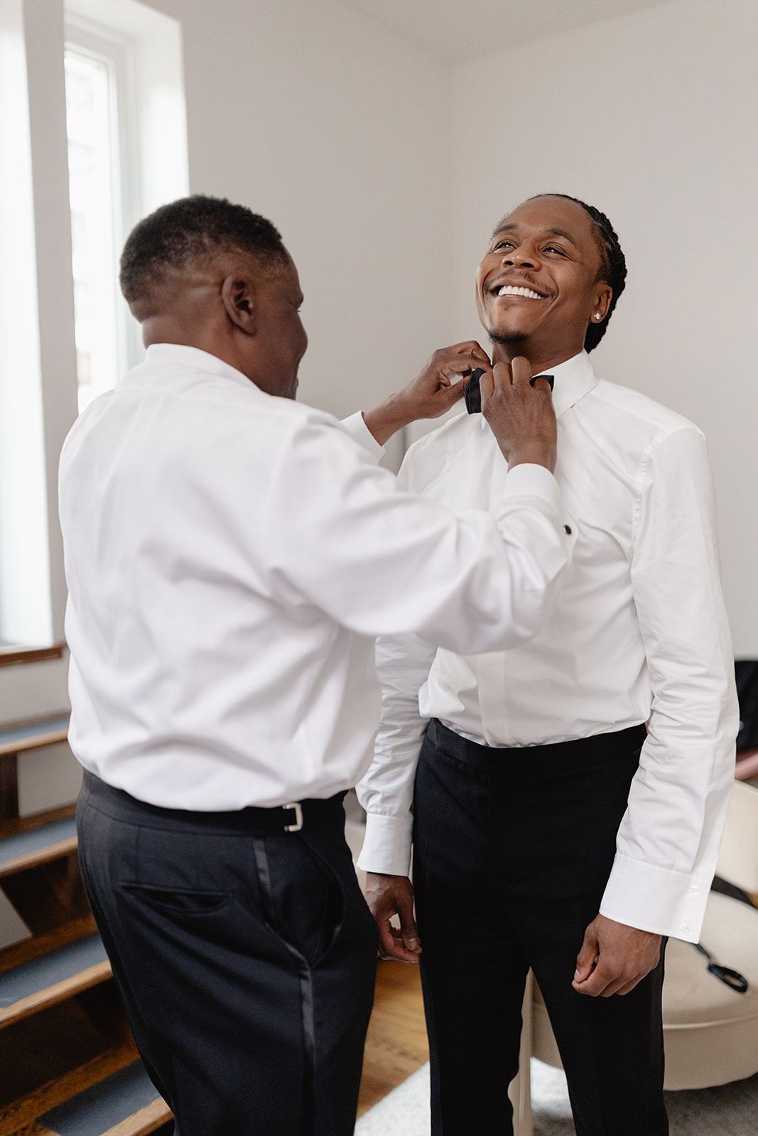 Older man helping the smiling groom adjust his collar