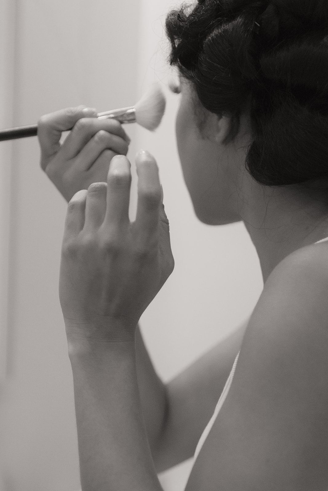 Bride applying her makeup with a brush, black and white