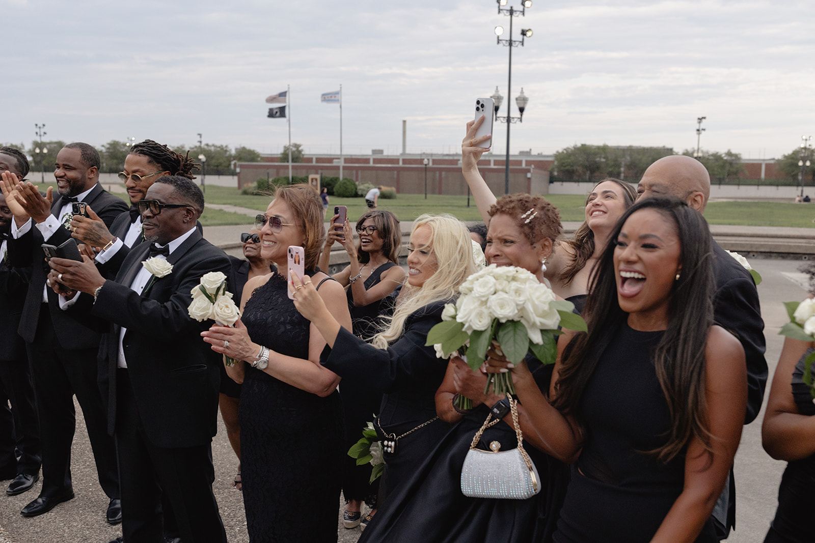 Wedding party cheering and filming with their phones in a park