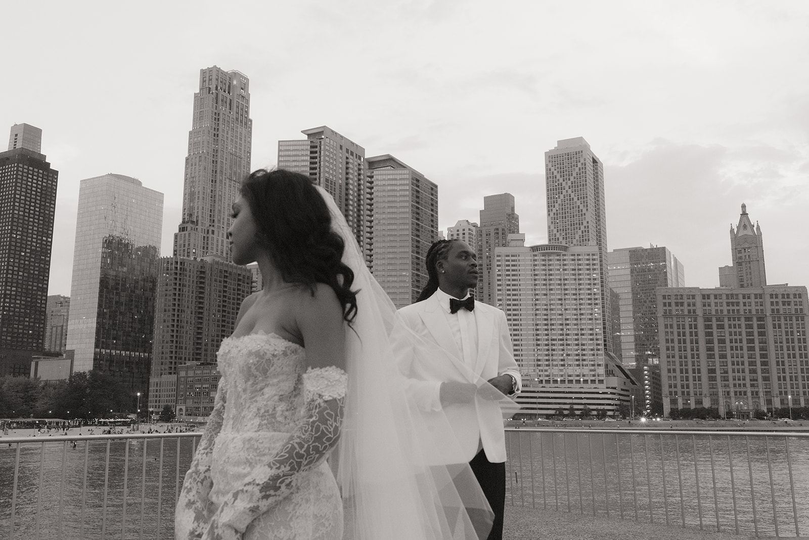 Bride and groom by a waterfront railing with the Chicago skyline behind
