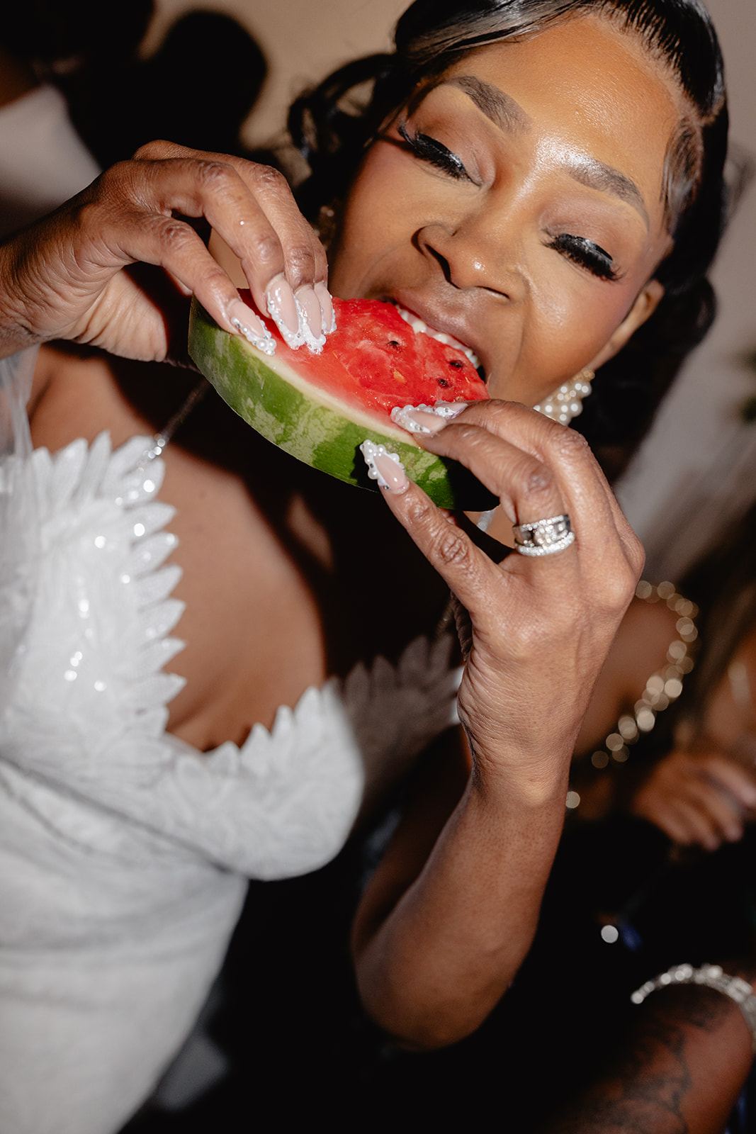 Bride laughing as she bites into a slice of watermelon