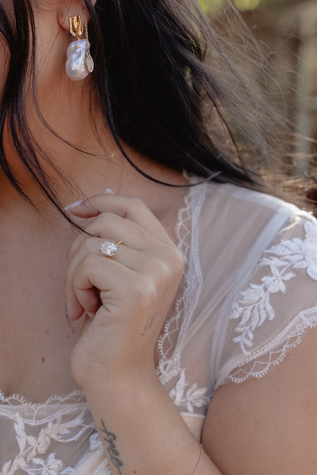 Bride touching her lace neckline, revealing her engagement ring