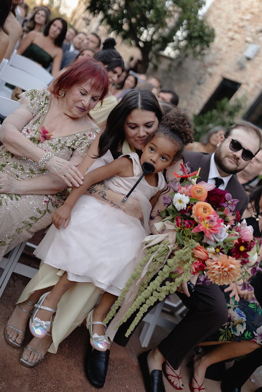 Guests watching an outdoor ceremony with a little girl on a lap