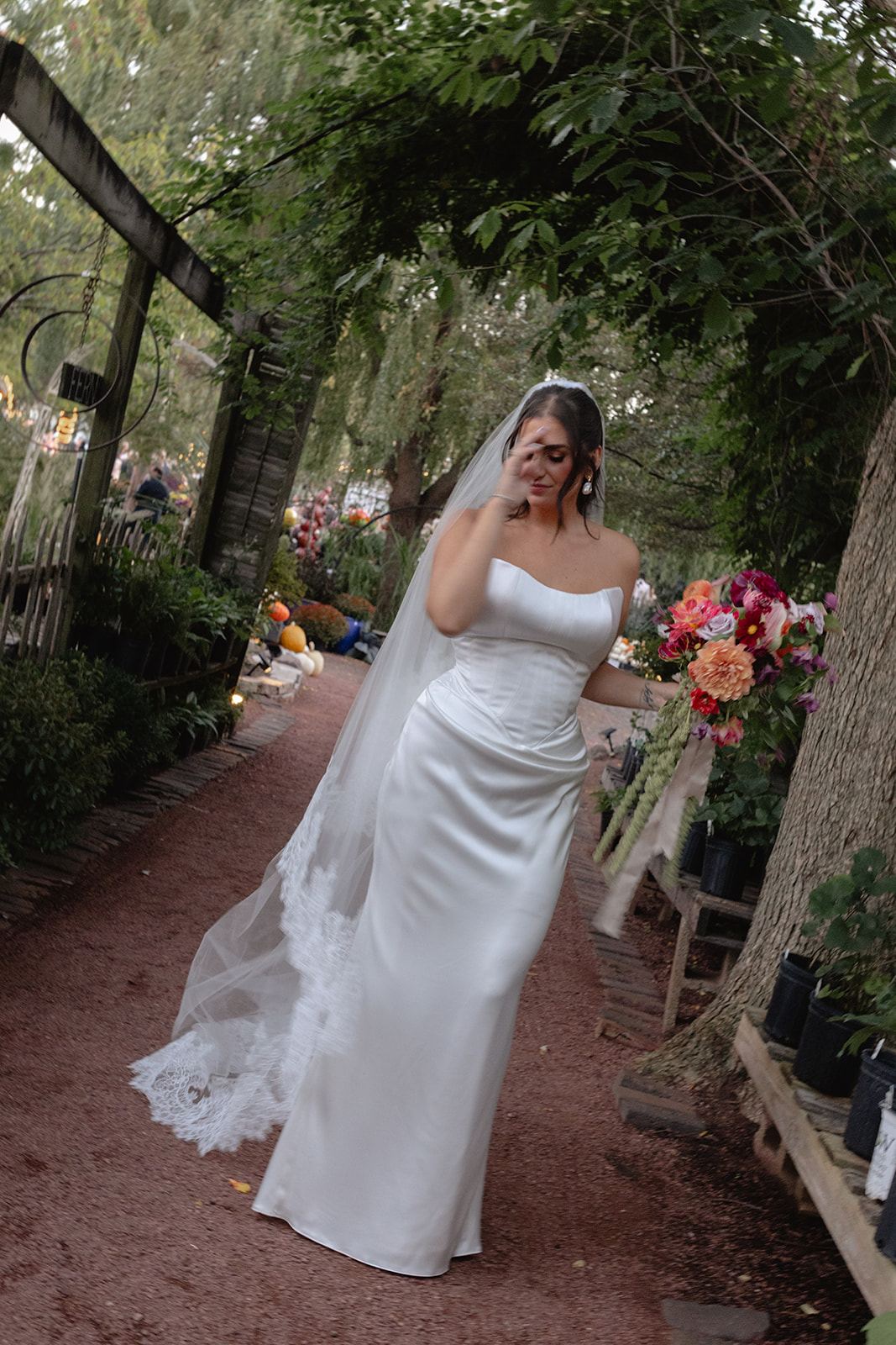 Emotional bride walking down a garden aisle under a leafy pergola