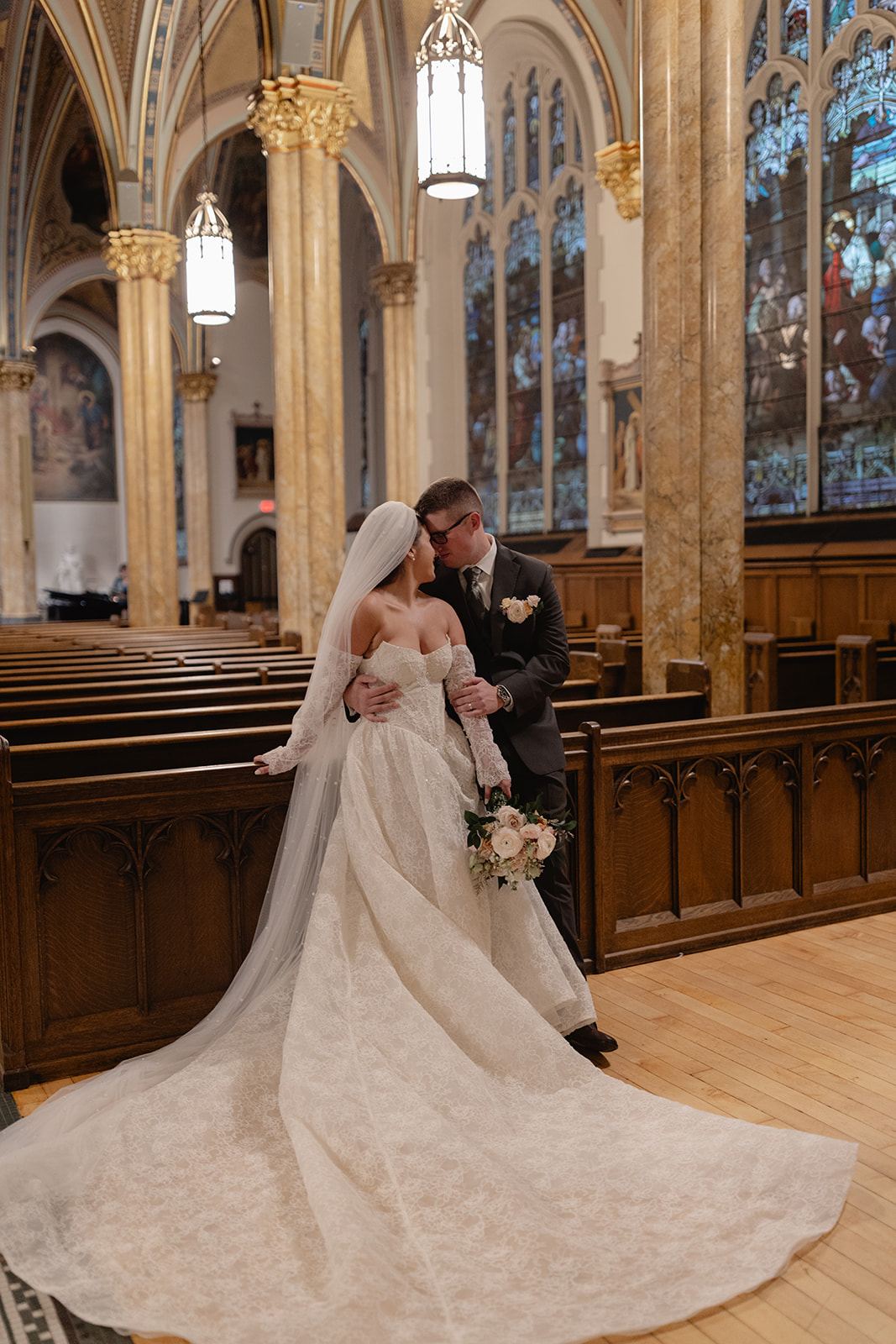 Bride and groom kissing in the aisle of a Gothic church