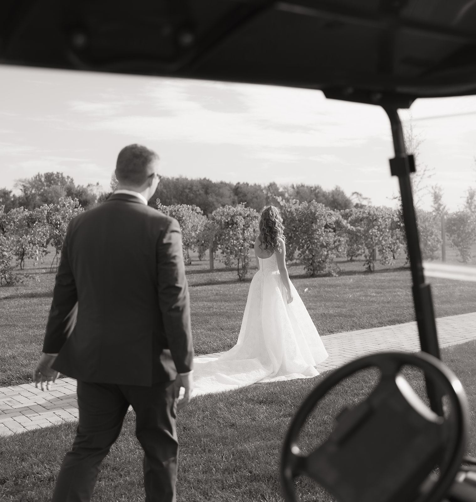 Groom approaching the bride on a lawn, framed by a golf cart