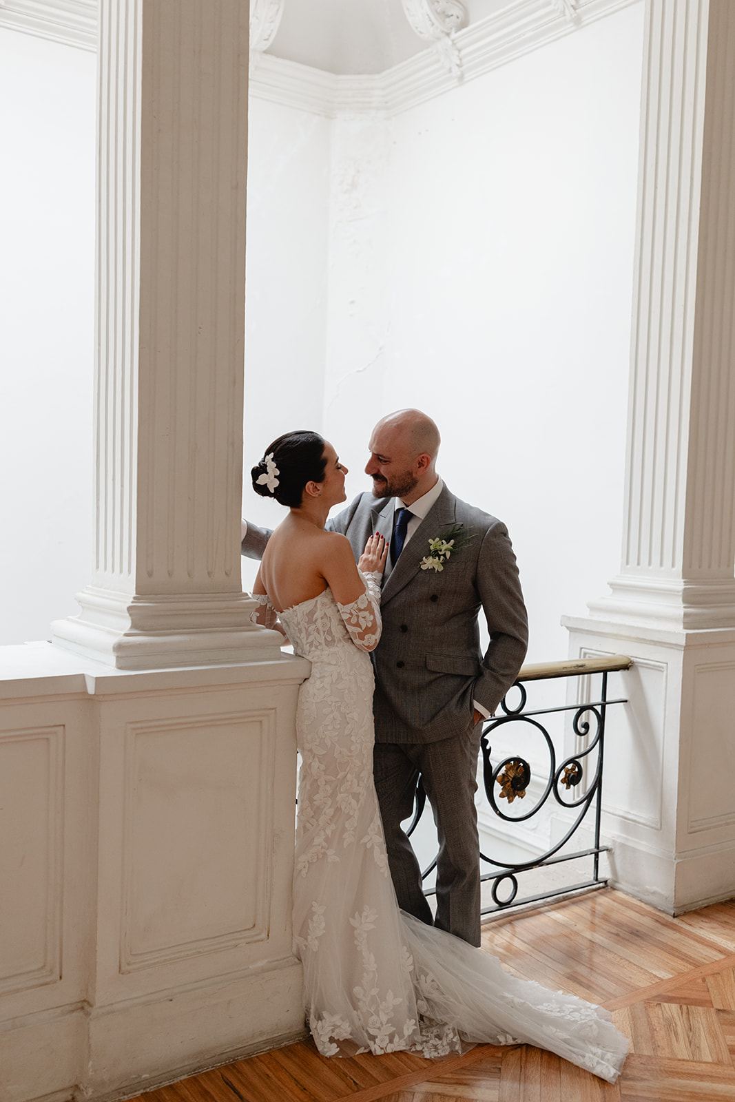Couple facing each other by white columns and a wrought-iron railing