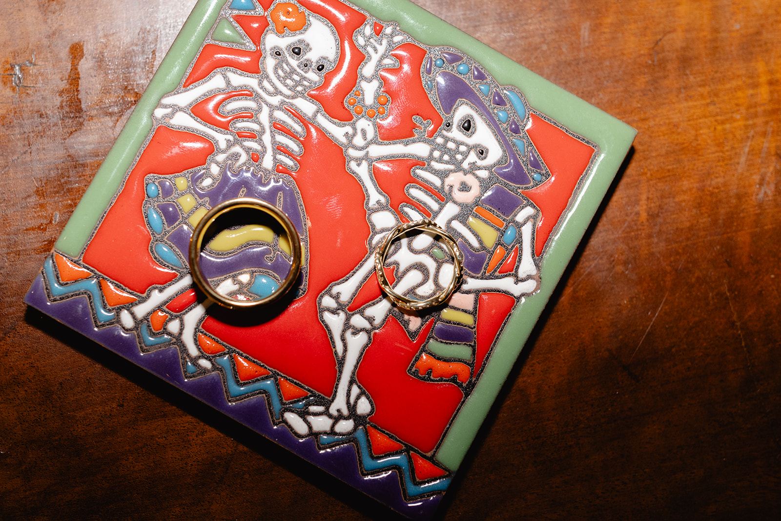 Two wedding bands on a colorful Day of the Dead skeleton tile